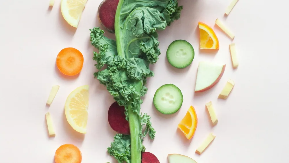 Kale, carrot, cucumber, beetroot, apple and citrus laid out on white - corporate wellness nutrition programmes in Cape Town